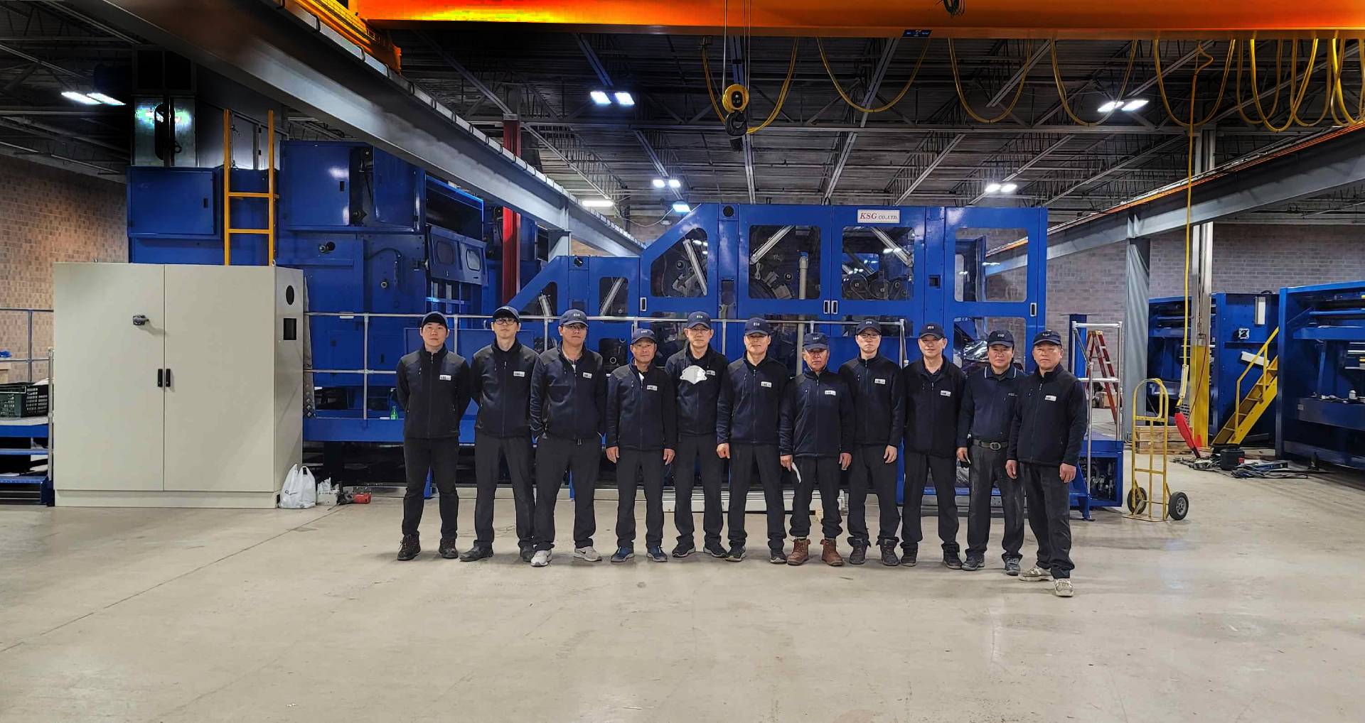 KSG engineering team in front of a nonwoven production line at the factory
